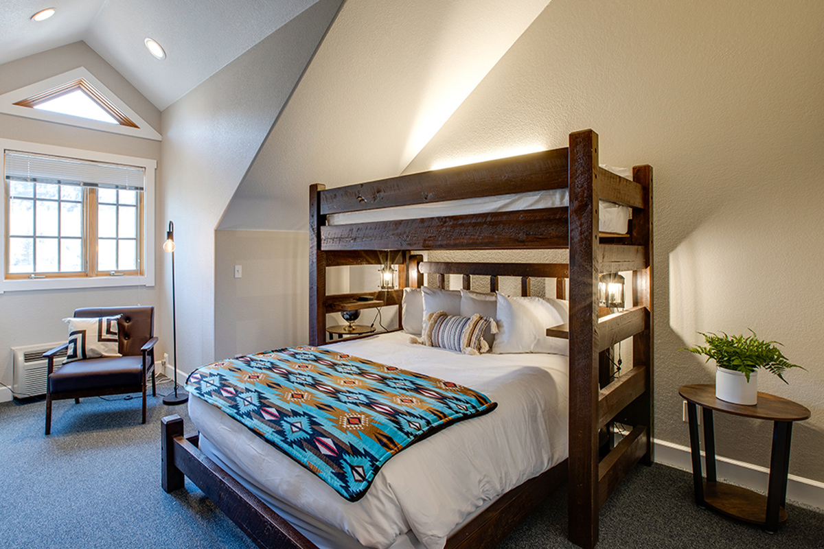 A turquoise and brown Native American-inspired blanket lies folded in half atop a thick mattress covered in white linens at The Bivvi Telluride in Colorado.