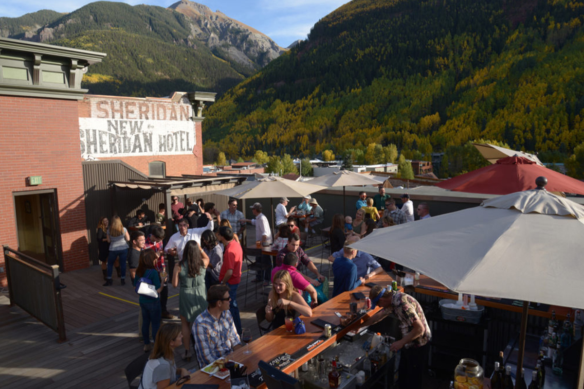 Crowds of hungry guests enjoy views of the mountains, tasty drinks and sunny skies on the rooftop of the New Sheridan Hotel in Telluride, Colorado.