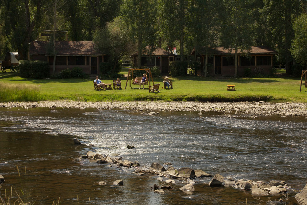 A family relaxes in log chairs and a log swing along the banks of the Colorado River at Bar Lazy J Guest Ranch.