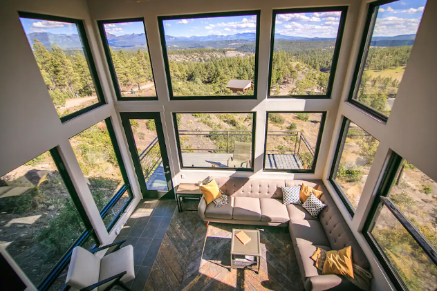The living room of The Ridge cabin in Pagosa Springs is filled with natural light from panoramic windows.