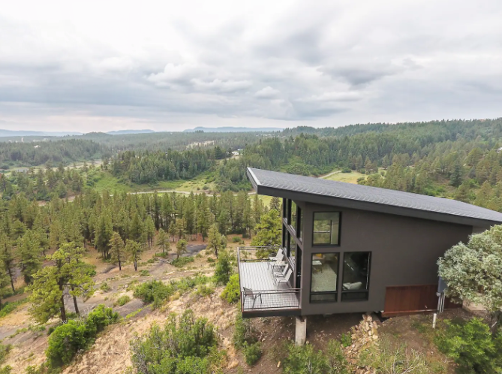 The side view of The Ridge cabin in Pagosa Springs with trees, shrubbery and a cloud-filled sky