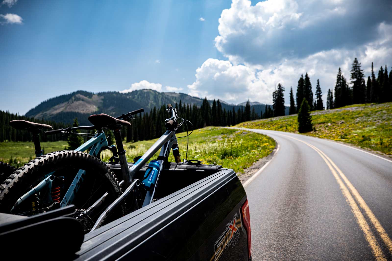 A truck with bikes in the bed driving down a road in Crested Butte