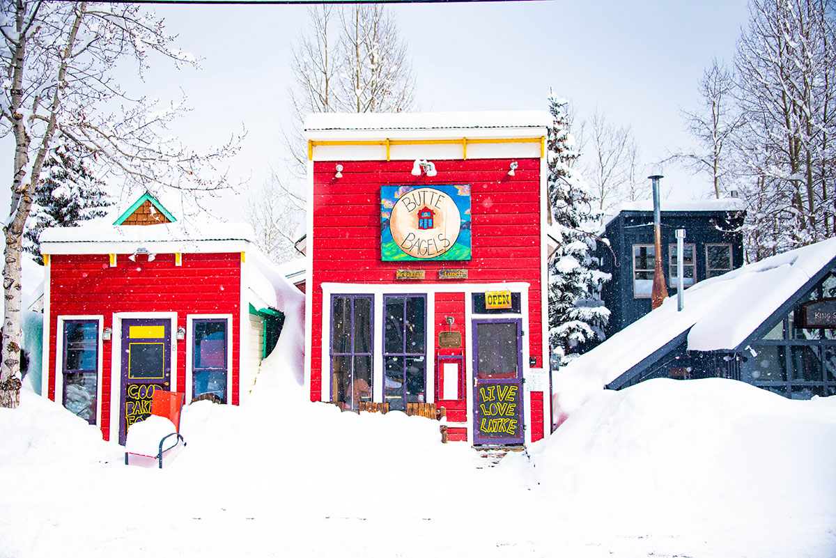 Two small red buildings on a very snowy street