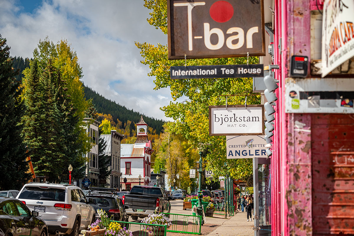 Street scene of shops and restaurants with a sign hanging overhead that reads "T-bar International Tea House"