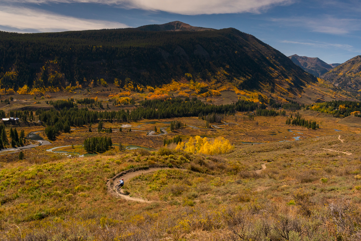 A mountain biker weaves down a windy trail lined with fall colors in Crested Butte, Colorado.