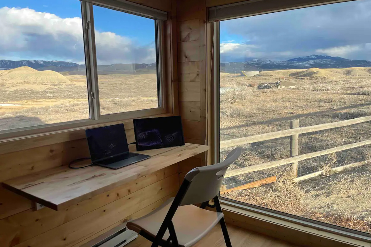 A small desk and chair create an office space in a tiny home in Montrose, Colorado. Massive windows create the illusion of working outside.