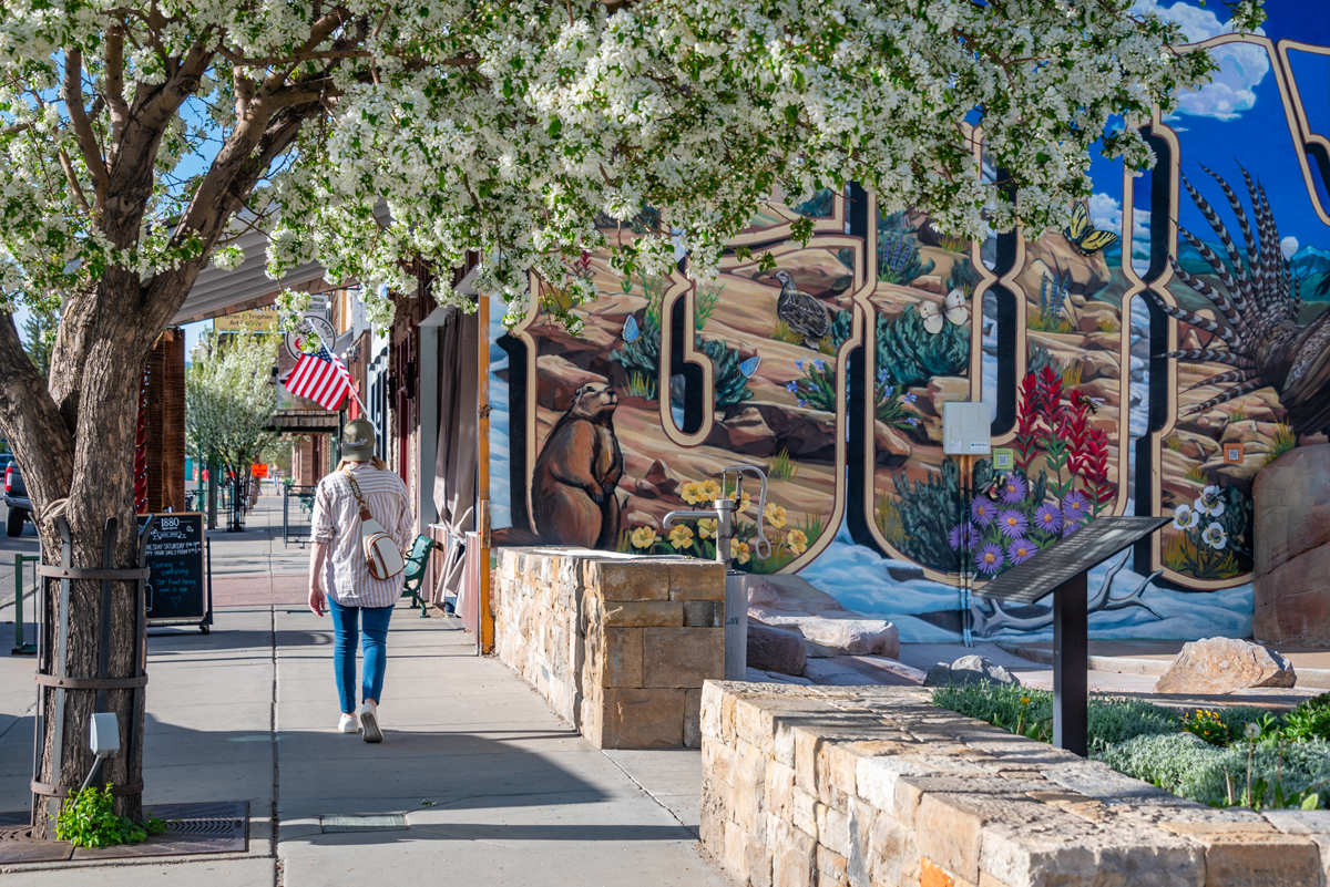 A person walks past a mural and shops in Downtown Gunnison, Colorado in spring