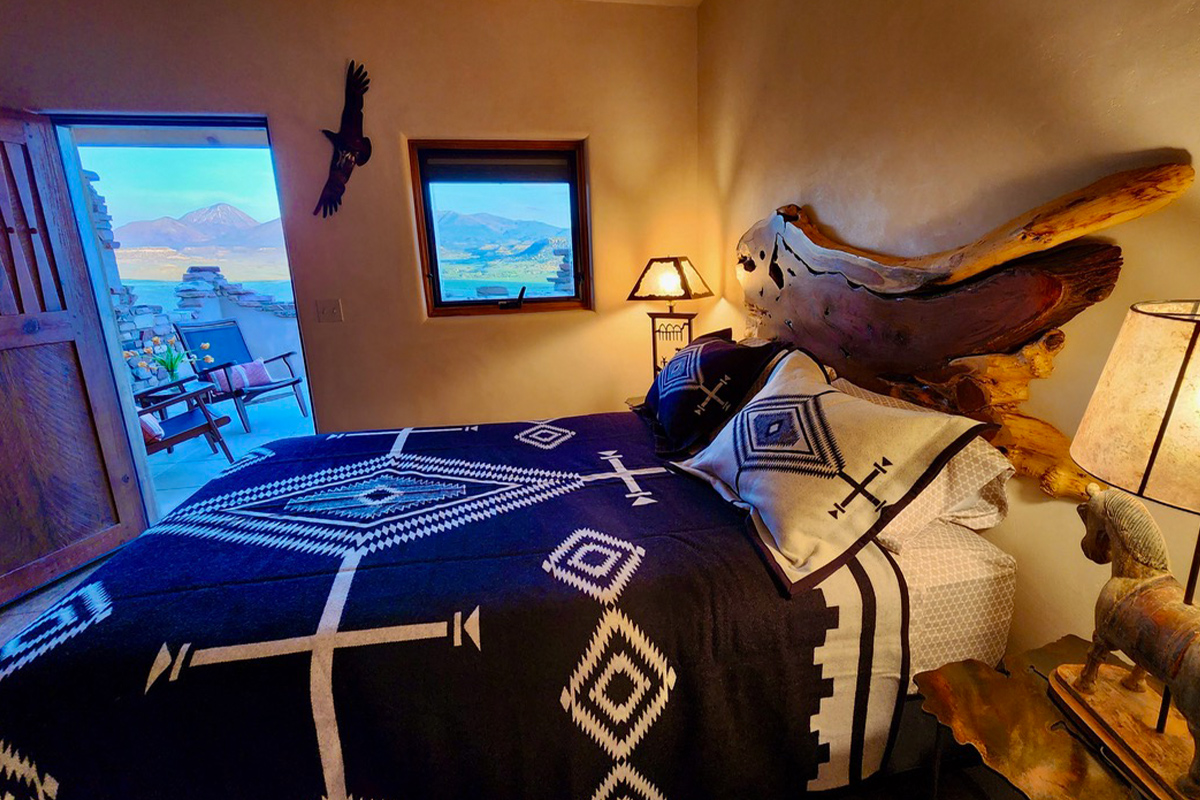 A guest bedroom at the Canyon of the Ancients Guest Ranch near Cortez, Colorado, feature Southwestern-style decor and opens out onto a stunning patio space.