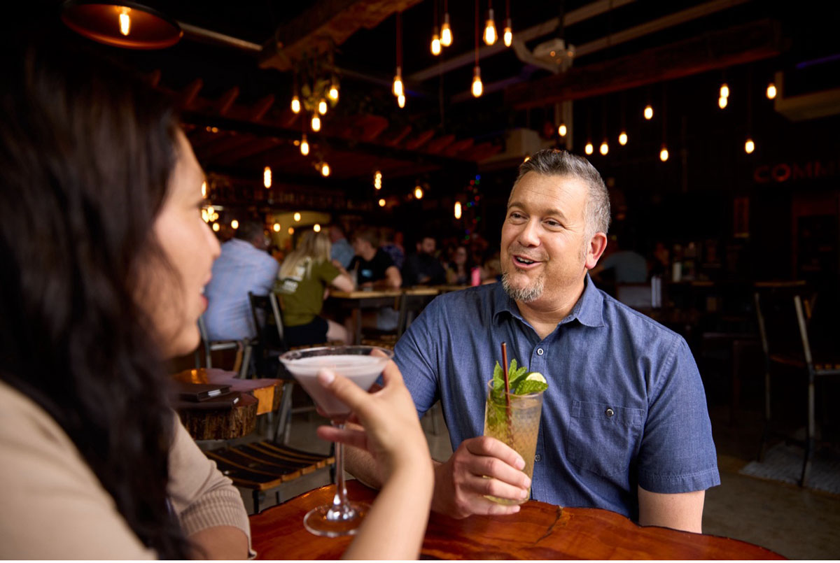 Smiling guests toasting cocktails inside Abbott & Wallace Distillery.