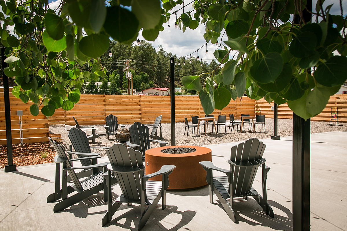 A set of Adirondack chairs sit around an unlit firepit, inviting people to chat and mingle at LOGE Wolf Creek.