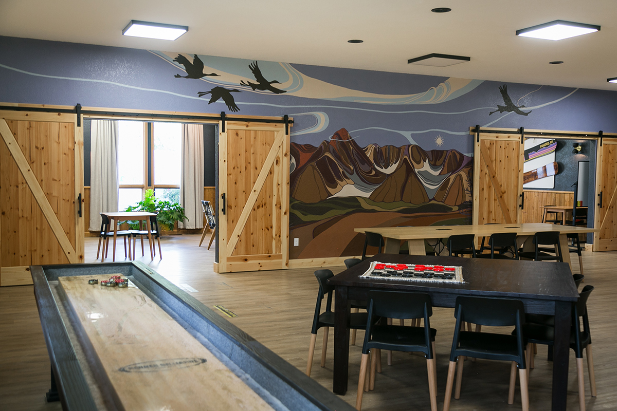 A communal space at LOGE Wolf Creek in South Fork features a nature mural with flying geese and spaces to play games and chat.