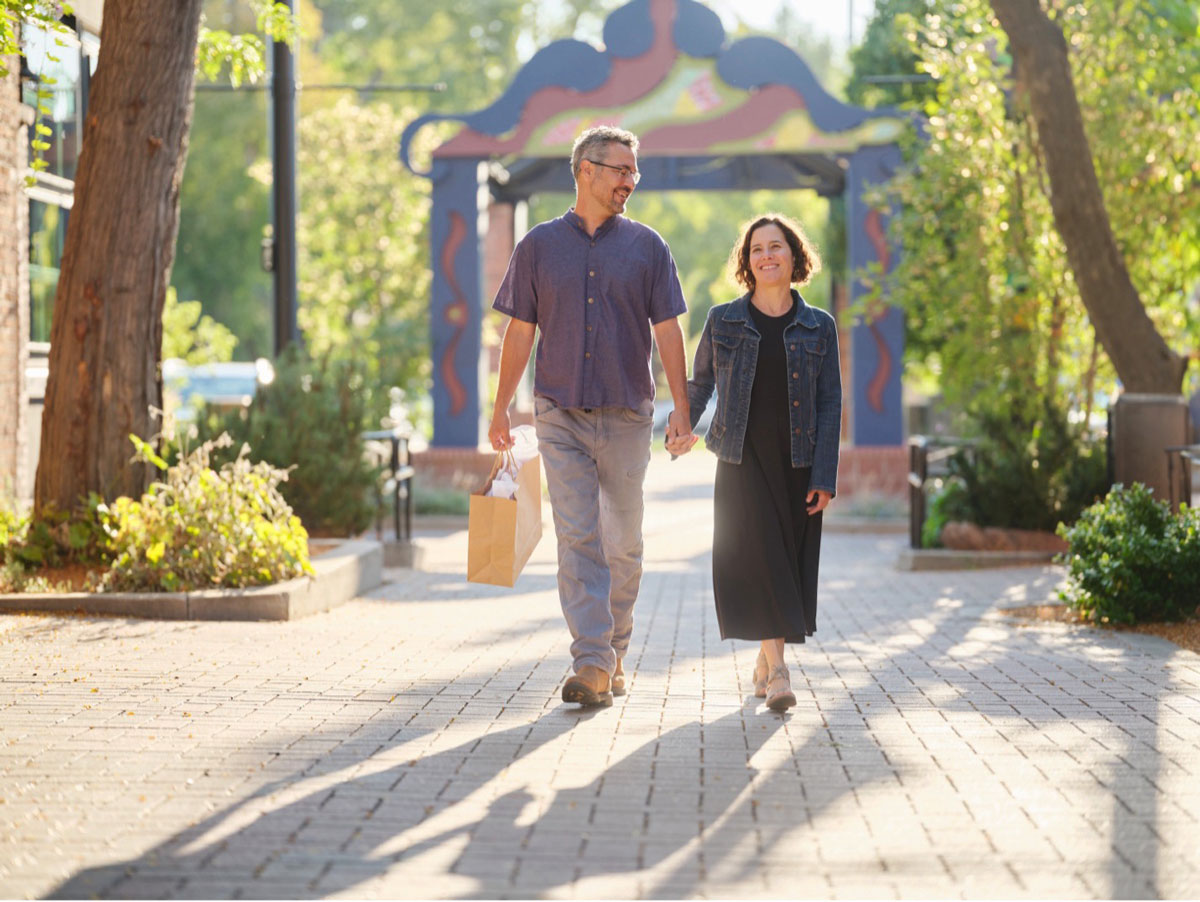 A couple strolling outside with a shopping bag, holding hands in Downtown Longmont in Colorado