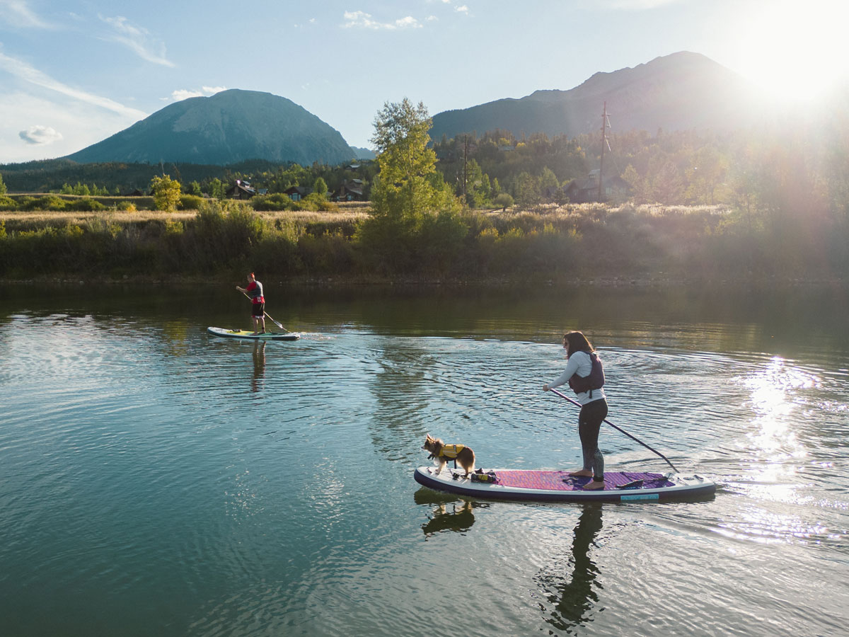 Paddleboarding across reflecting waters with mountain views on a sunny day