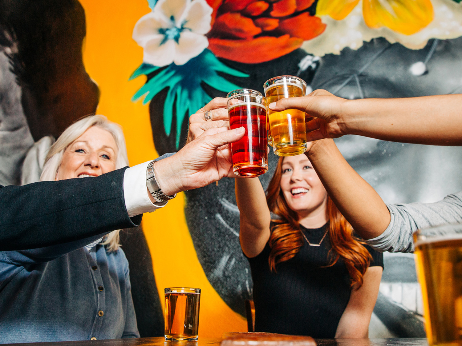 People raise golden and red glasses of beer in a cheers at Lady Justice Brewery in Aurora, Coloraod. 