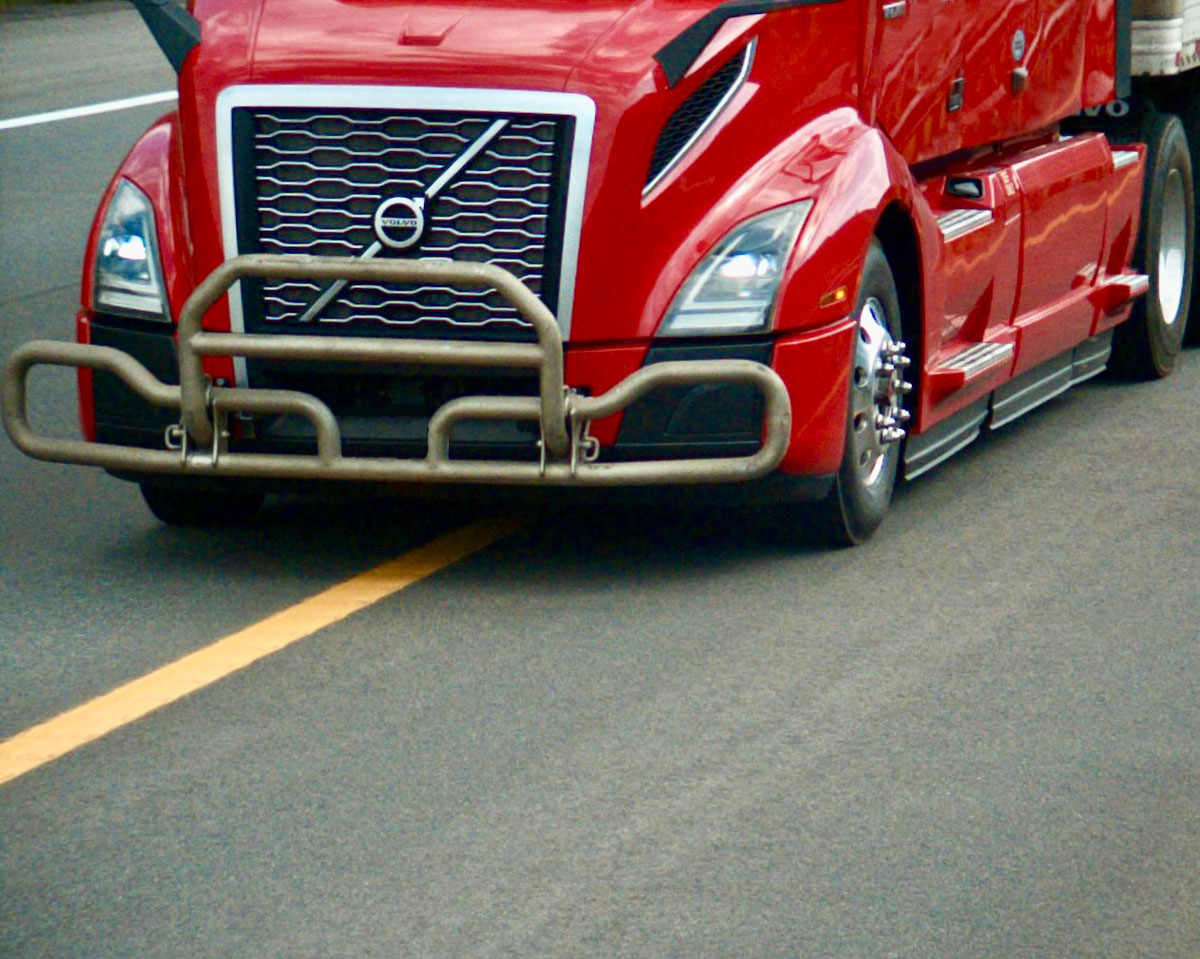 A red semitruck crossing a solid-yellow line, violating a Colorado Express Lane rule.