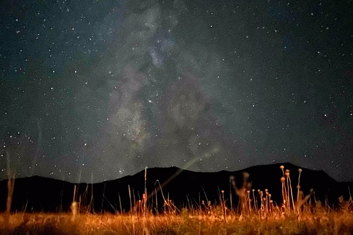 A sky filled with stars and swirls from the Milky Way stretches out over an open meadow near Westcliffe, Colorado.