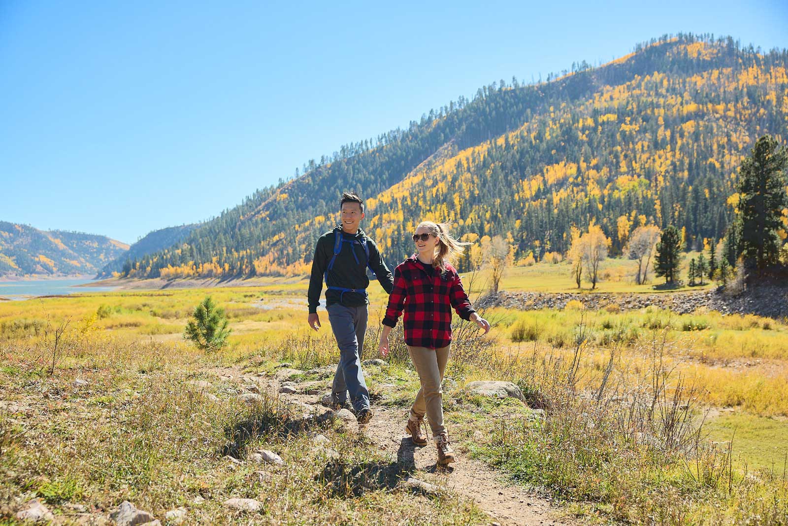 Two people walk on a dirt trail amid a sea of fall colors and foliage near Durango