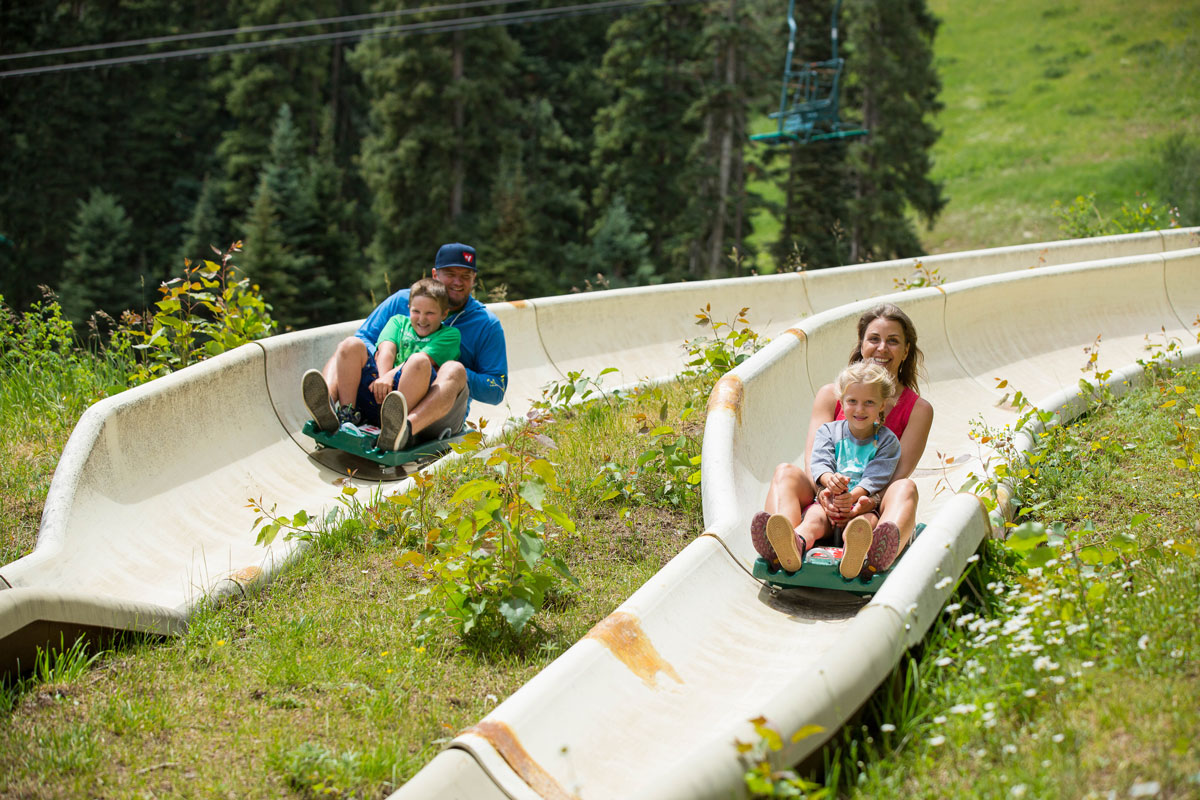 Family laughing while rising down the alpine slide on a summer day at Purgatory Resort in Durango.