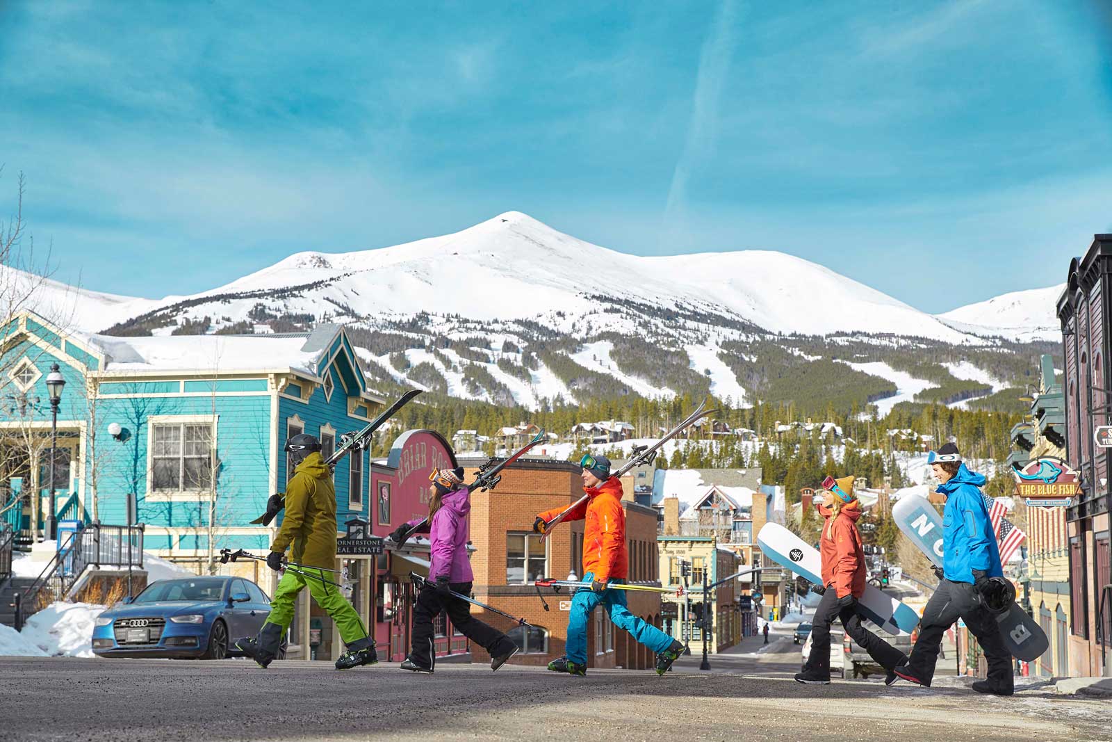 A family in ski gear crosses a street in Breckenridge near colorful buildings