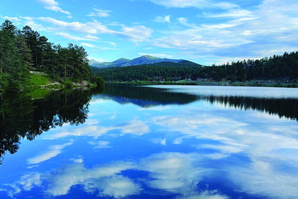 Calm waters of Evergreen Lake, reflecting the sky with tall pine trees surrounding it.