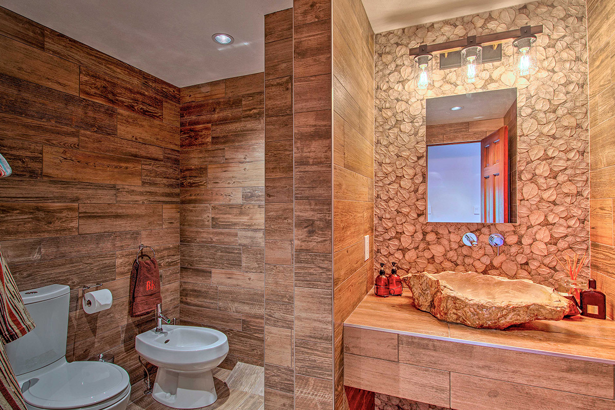 A stunning en-suite bathroom at Barret House features a stunning petrified wood sink and other nature-themed elements.