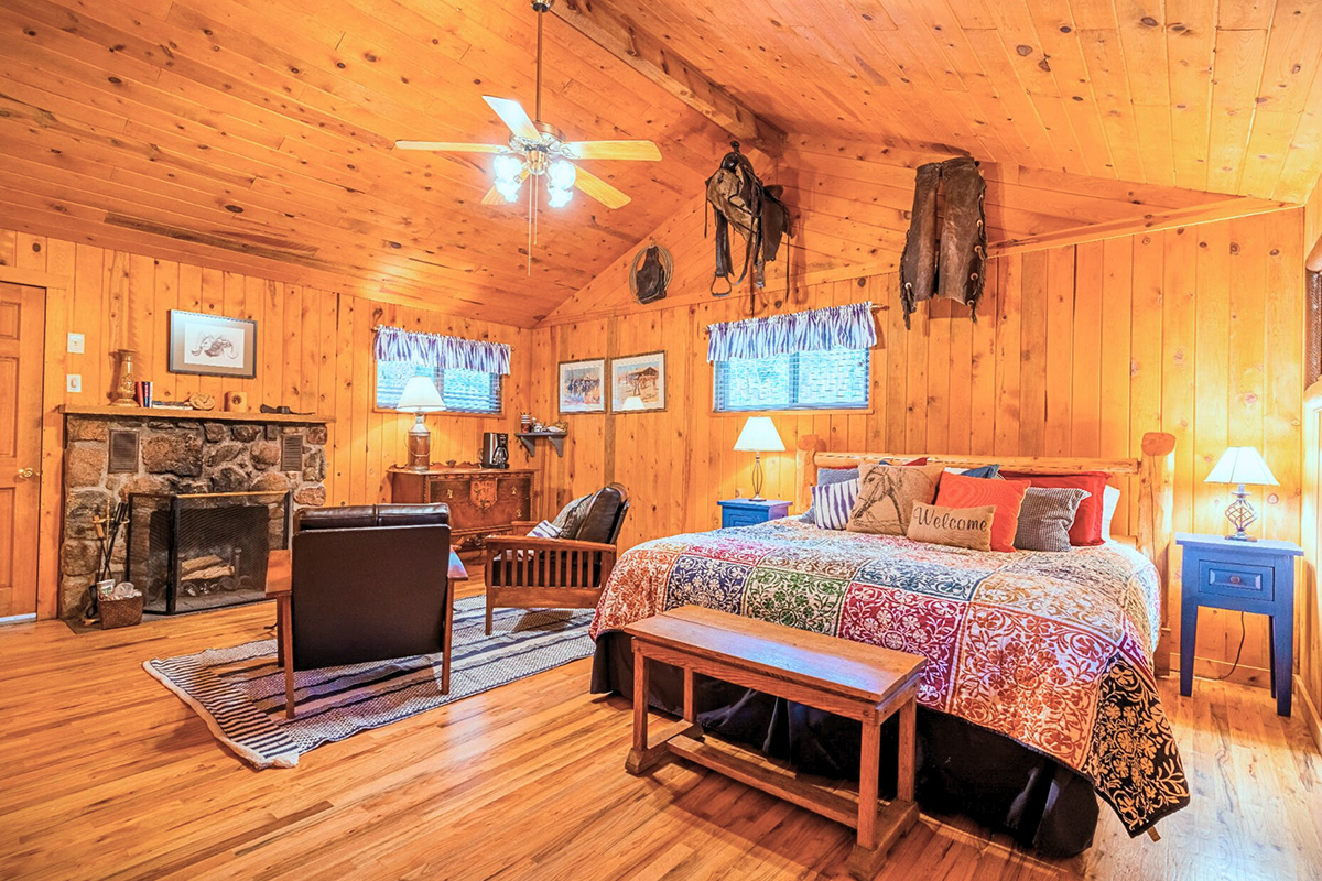 A guest cabin at Tumbling River Ranch near Grant, Colorado, features buttery, knotty wood-panel walls, a stone fireplace and cowboy decor.
