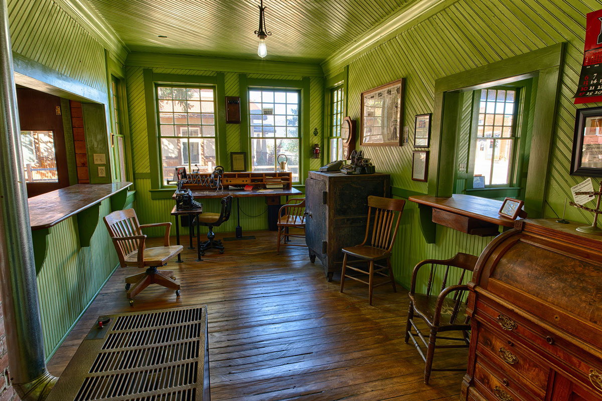 Bright green interior of All Aboard Westcliffe in Colorado, filled with vintage displays and furniture.