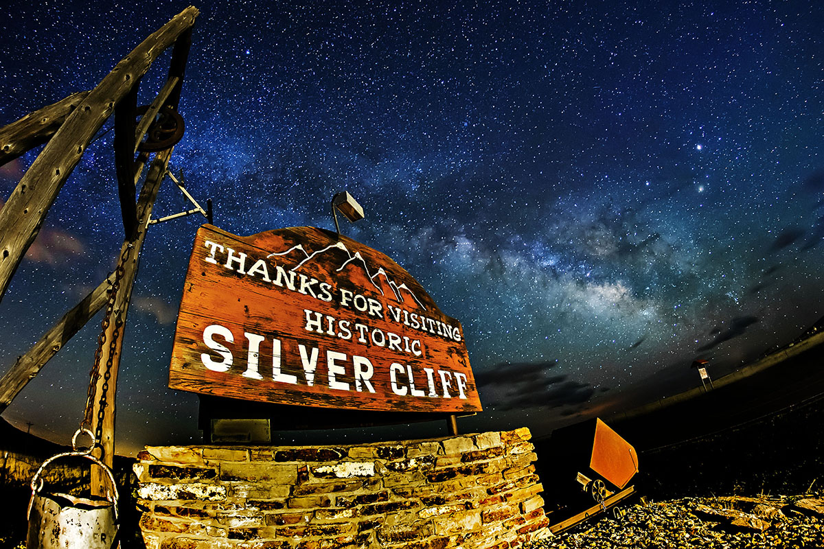 A rustic sign reading "Thanks for visiting historic Silver Cliff" at night with stars shining bright high above.