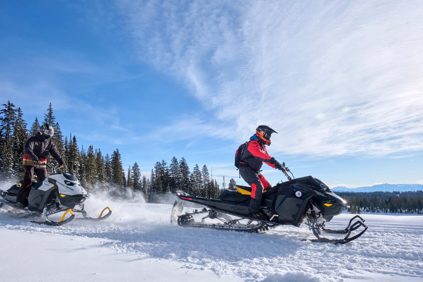 Two snowmobilers cruise through a snowy field on Colorado's Grand Mesa