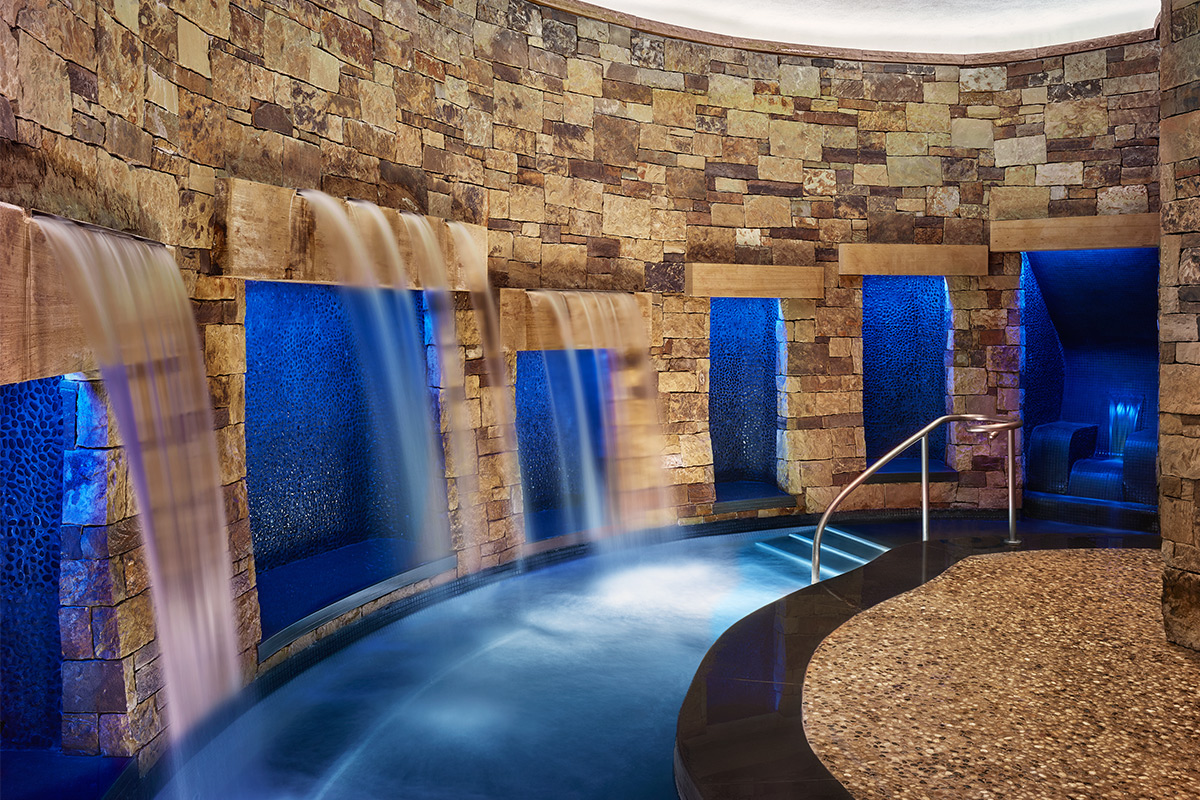 A spa area at the St. Regis Aspen Resort features small cascading water features and blue-lit stone alcoves.