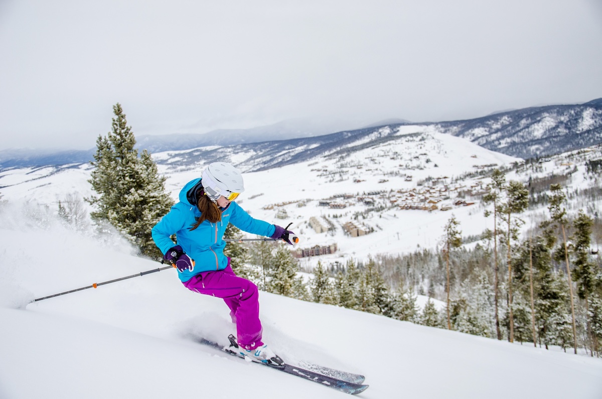 Skier in blue and purple outerwear skiing downhill near Granby, Colorado.