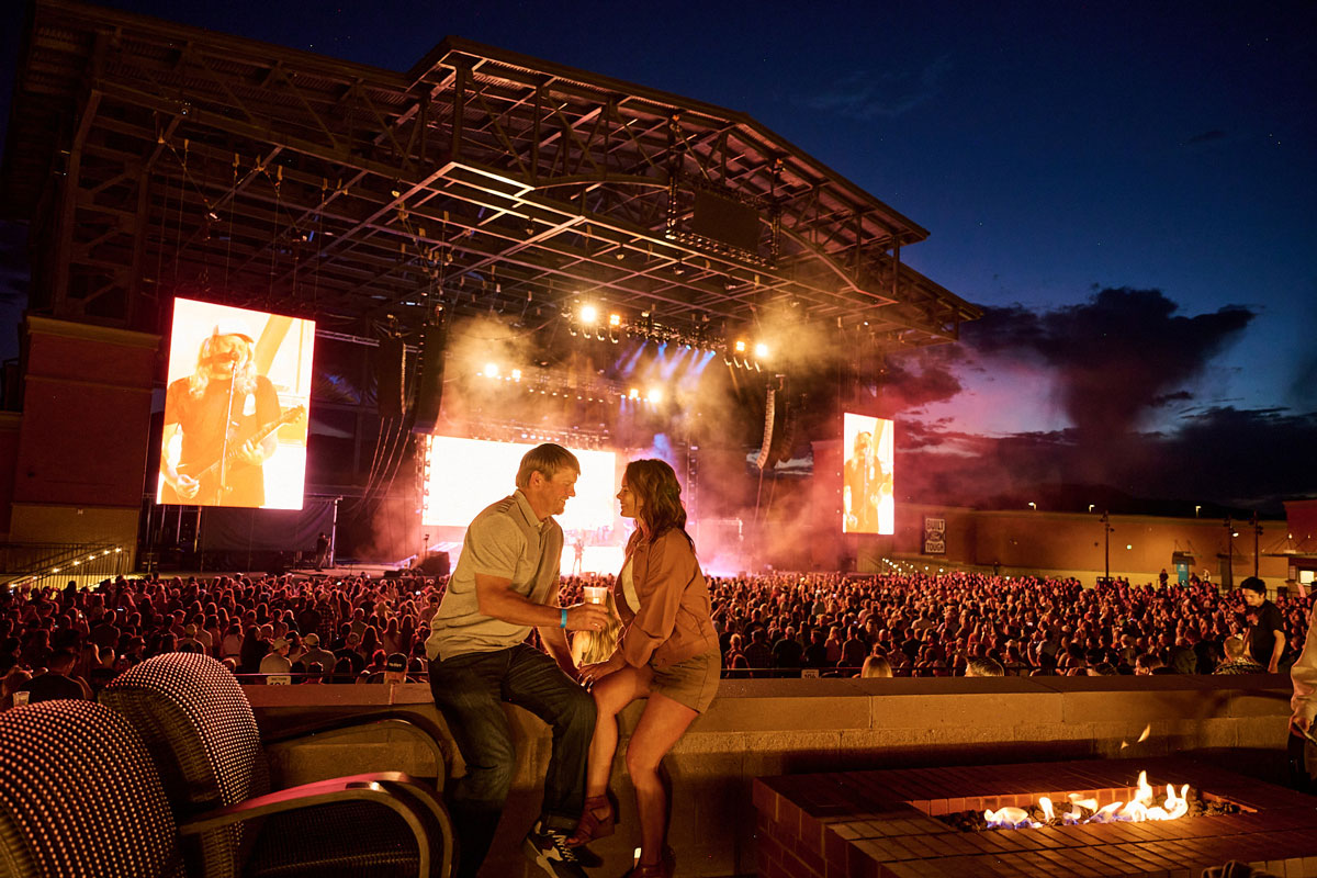 A couple sits overlooking a packed crowd at an outdoor concert at Ford Amphitheater in Colorado Springs