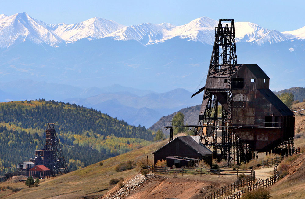 Historic mine structures in Victor, Colorado with mountains in the background