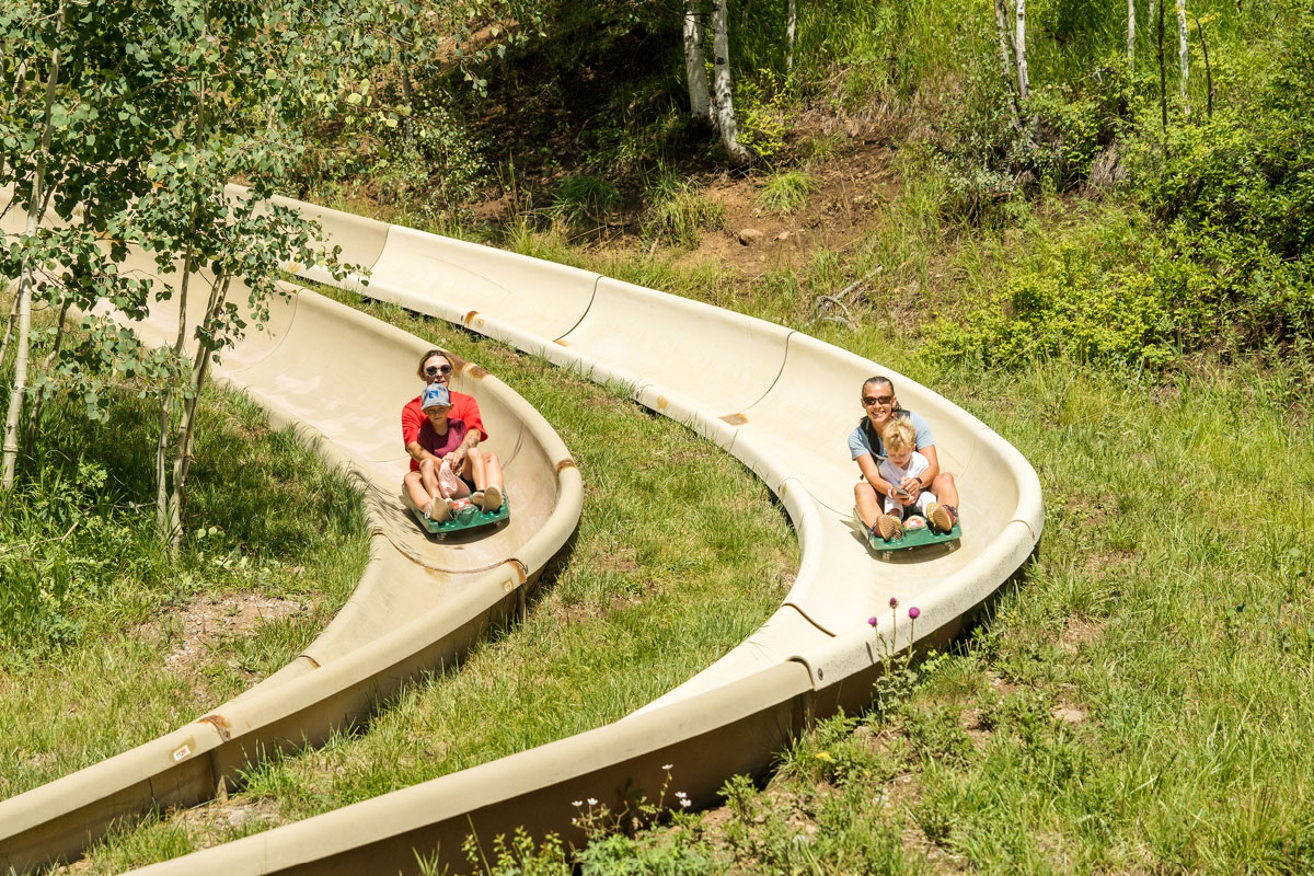 Adults and children descend parallel tracks on the Alpine Slide at Purgatory Resort.