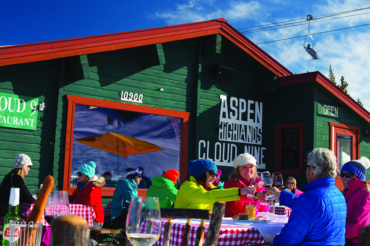 Diners sit outside at tables with checkered tablecloths at Aspen Highlands Cloud Nine in Aspen, Colorado.