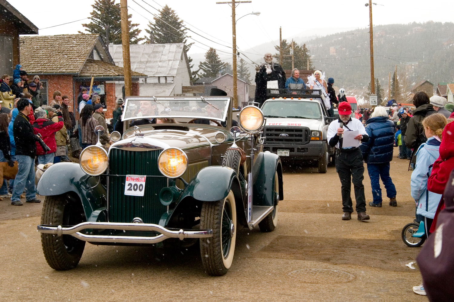 Vintage cars drive down the street at the Frozen Dead Guy Days parade in Nederland