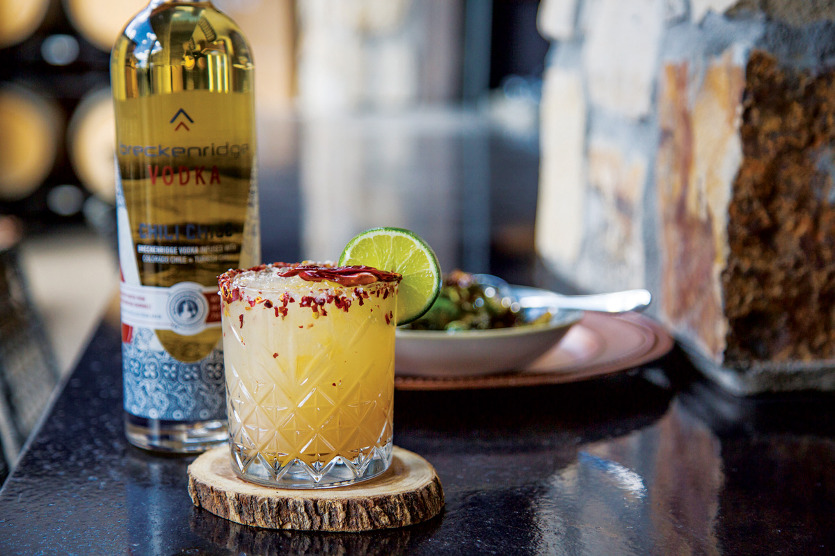 A spice-rimmed margarita and bottle of tequila on a restaurant table