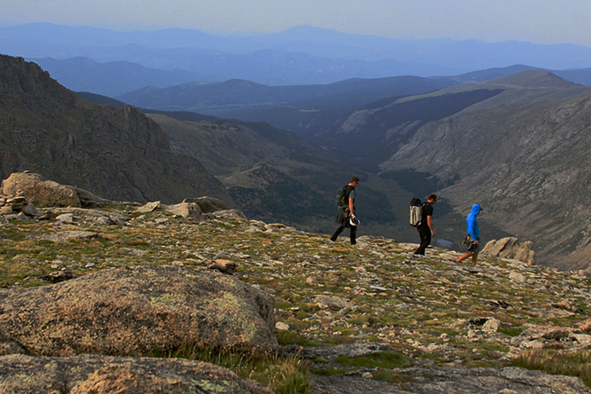 People hiking across a high mountain ridge in front of soaring mountains inClear Creek County