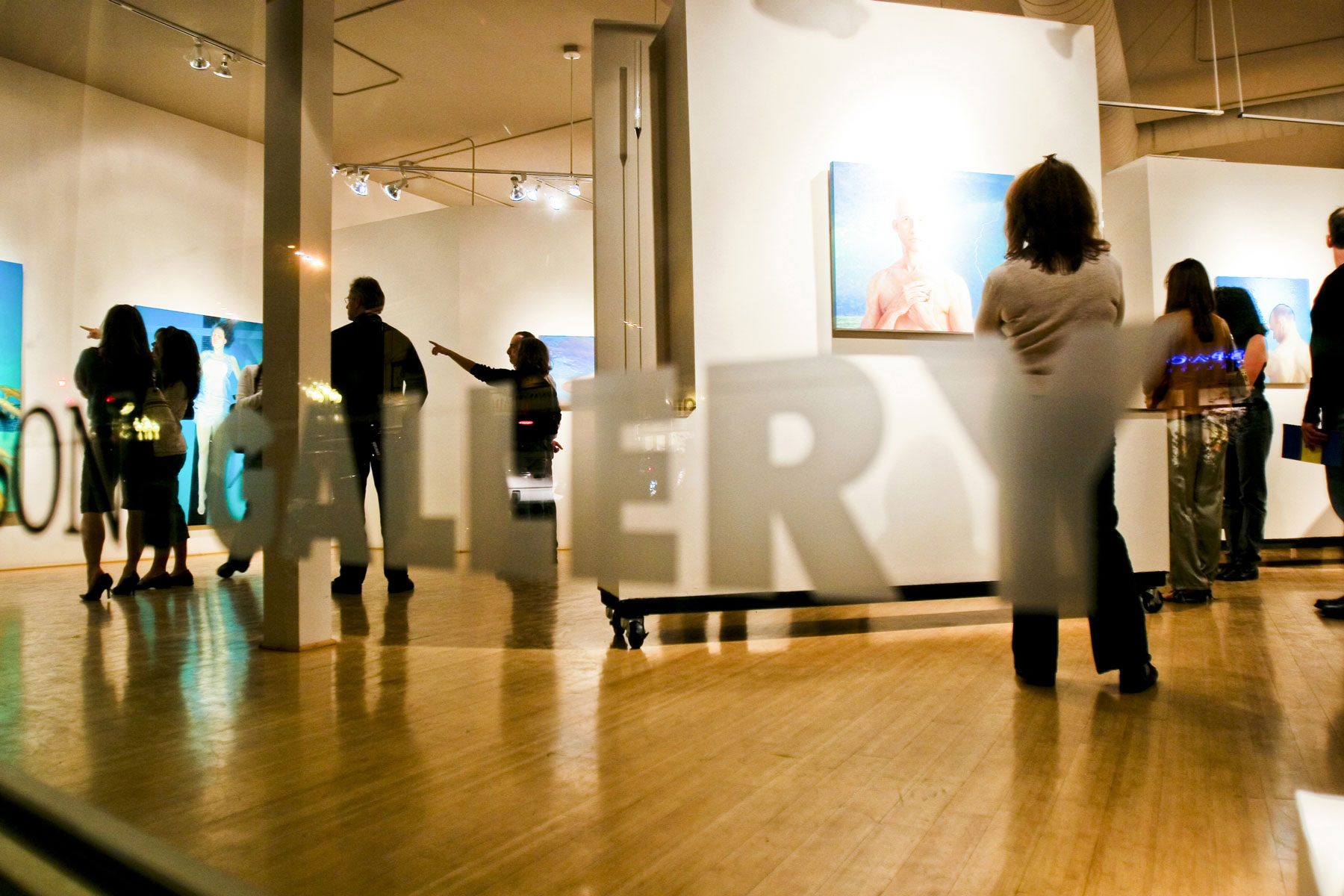 Art enthusiasts mingle and chat or stand and stare as they admire the various works hung on the white walls of an art gallery in Denver, Colorado.