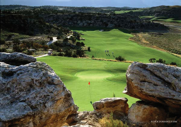 Bright-green fairways glow between red-rock outcroppings and patches of bushes and scrub brush; on on hole, a red flag flaps in the wind