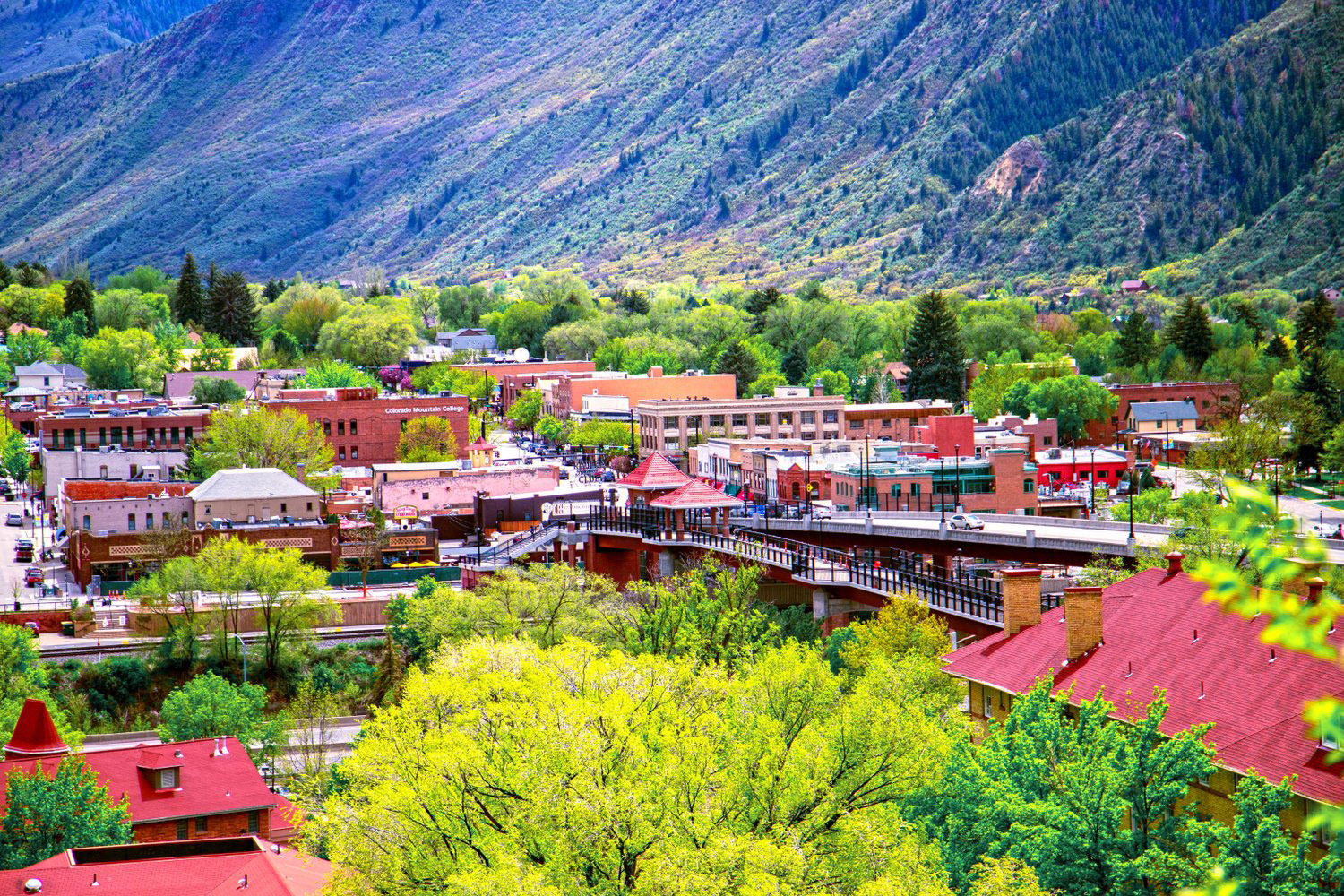 The many red-brick and red-roofed buildings of Glenwood Springs, Colorado, stand out against the green foliage throughout the town.