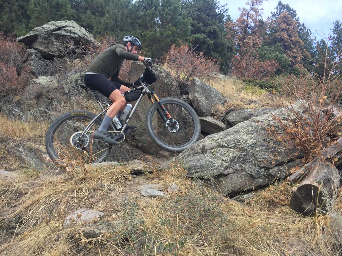 A bikers peddles uphill over large stones and rocky areas in a section of Colorado's Rocky Mountains.