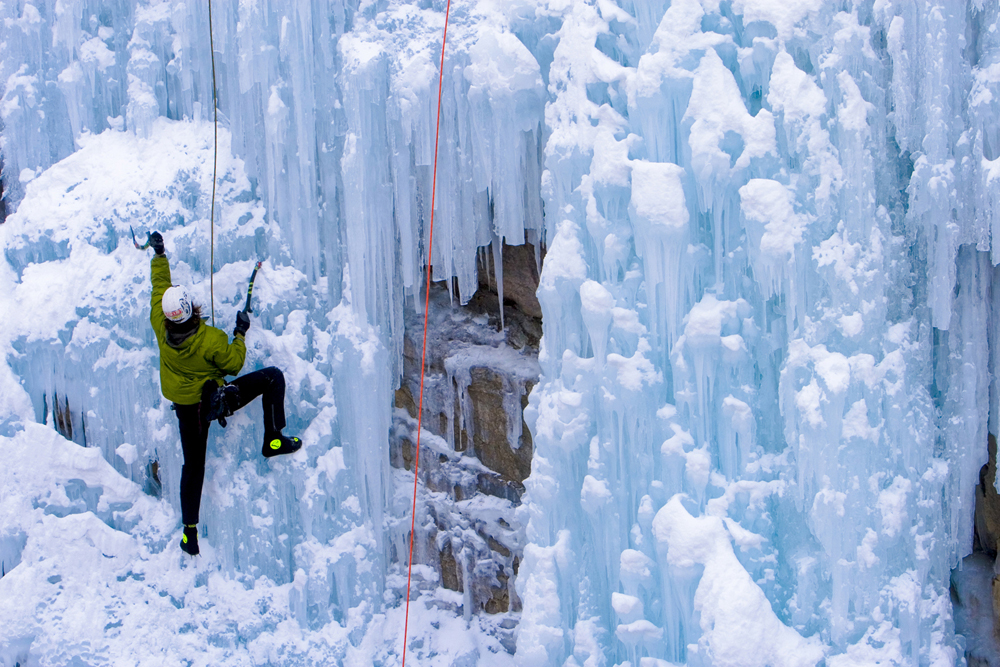 A determined climber uses sharp, hooked tools to scale a wall of snow-covered ice near Ouray, Colorado.
