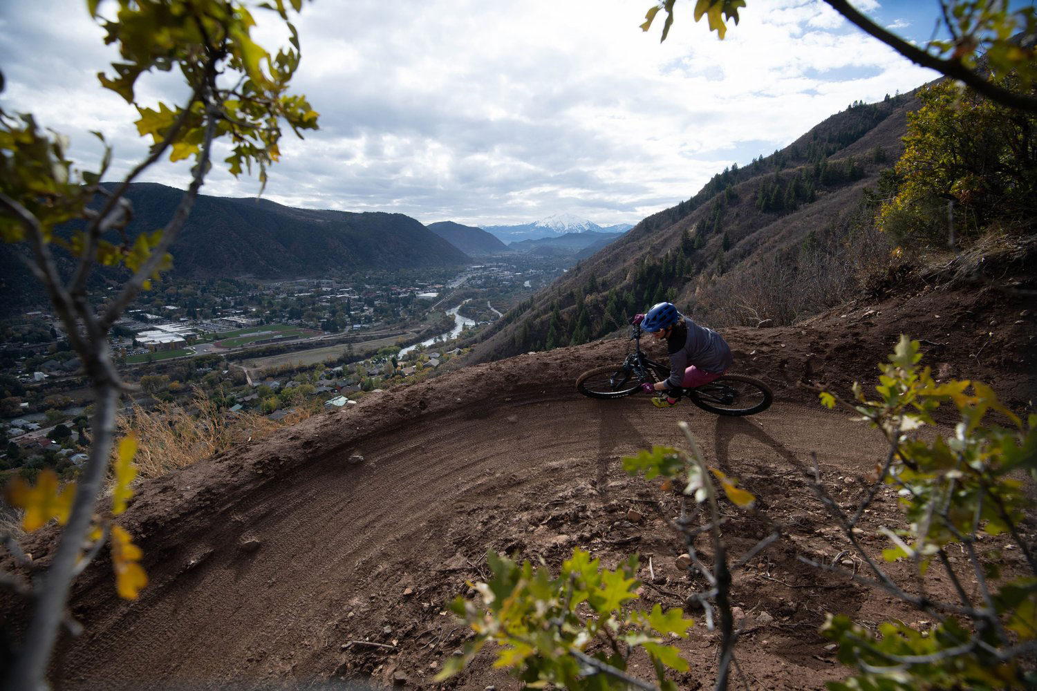 A mountain biker taking a tight turn around a switchback over the Roaring Fork Valley