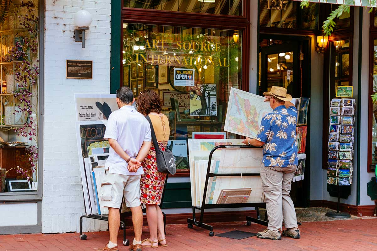 People checking out Art Source posters on Pearl Street on a sunny day