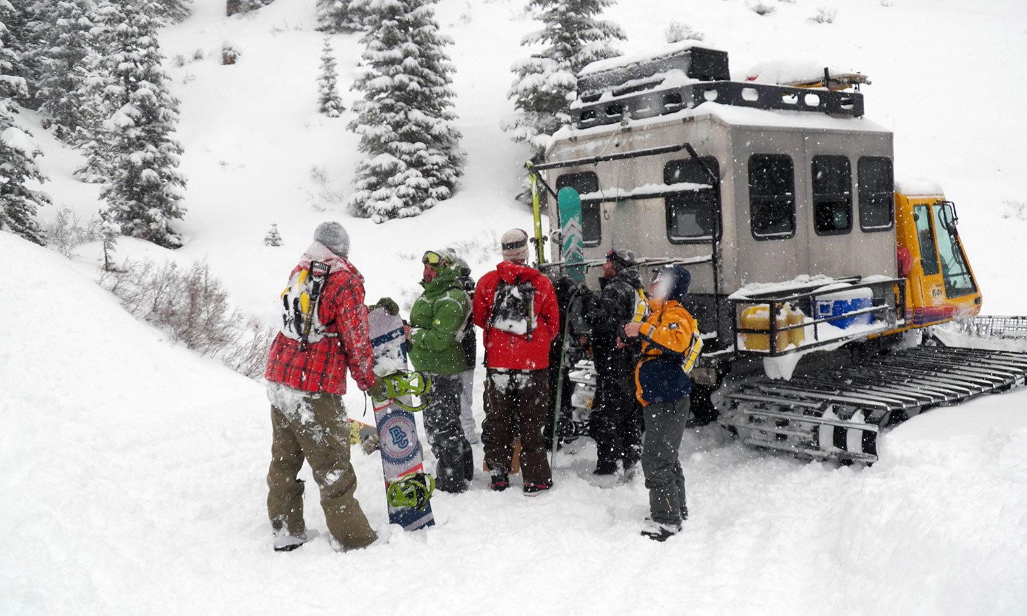 Snowboarders preparing for a guided backcountry tour next to a snowcat in Colorado.