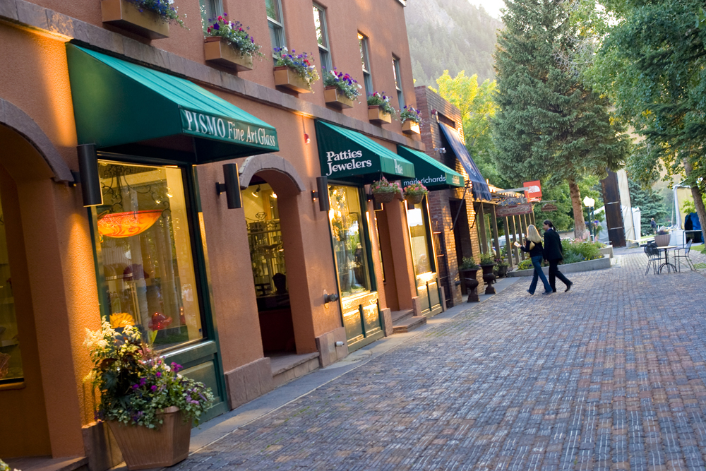 People walk along a brick-lined street full of stores