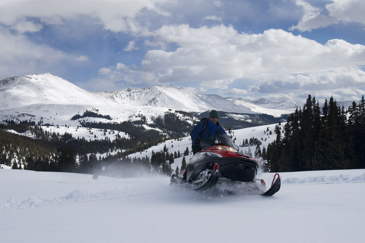 A snowmobile races across a mountain trail