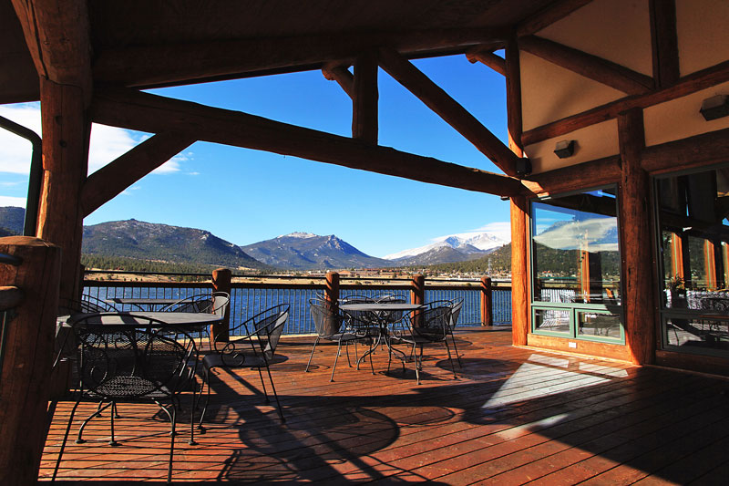 View of a blue lake a rolling blue hills from the outdoor dining section of lodge. 