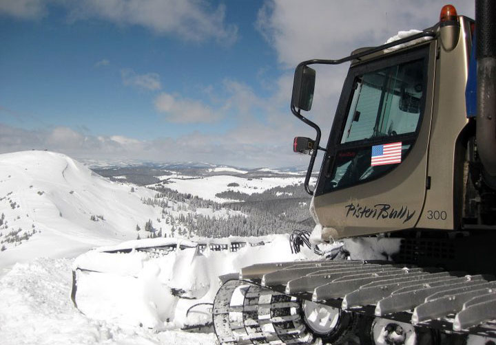 Closeup of a snowcat perched on a snowy slope, overlooking a wintry landscape in Colorado.